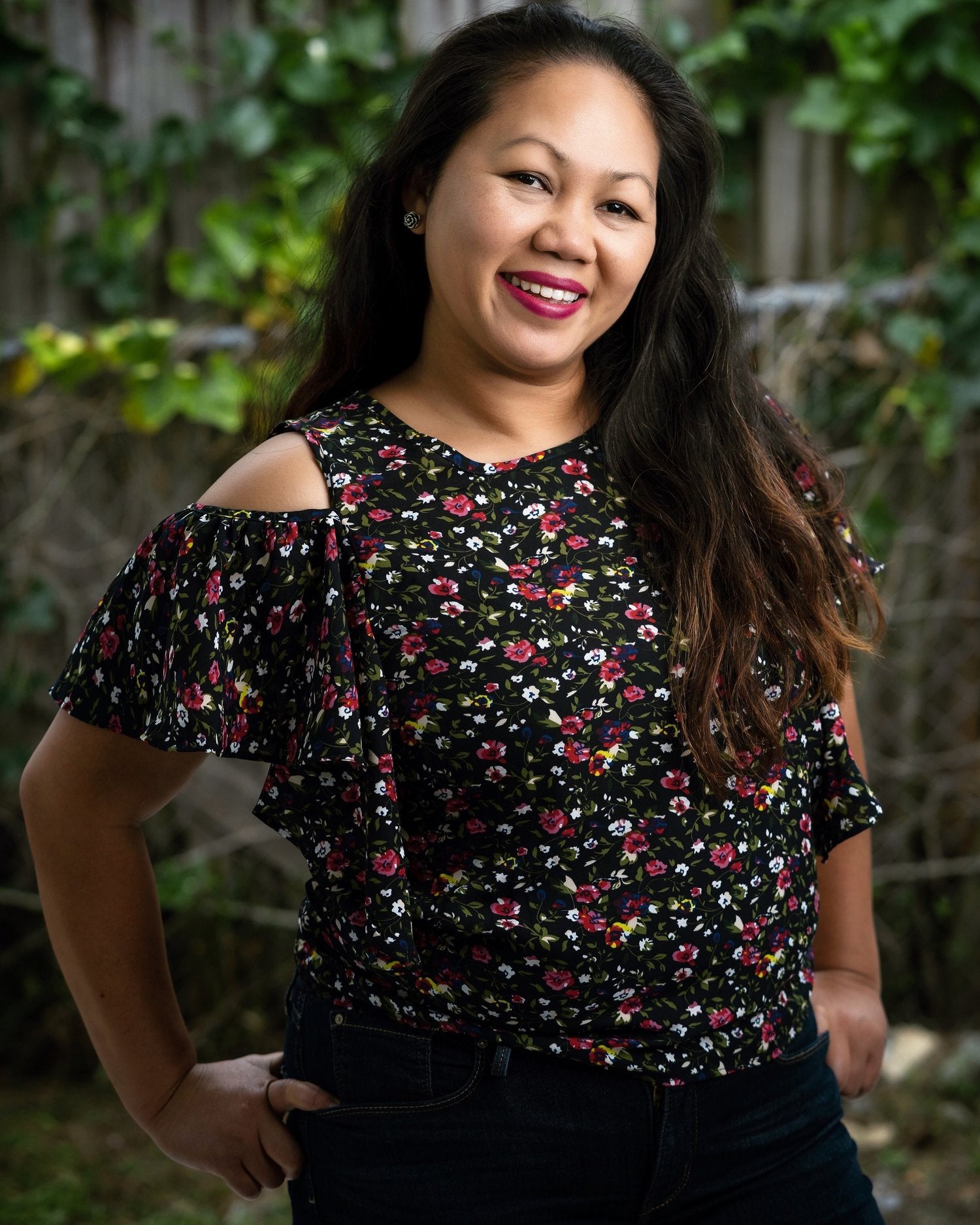 Artist Loy wearing a floral off-shoulder top with a blurred natural background