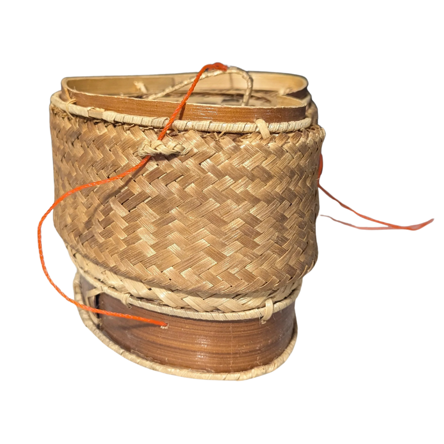 Woven rice basket with a spool of orange thread on a white background