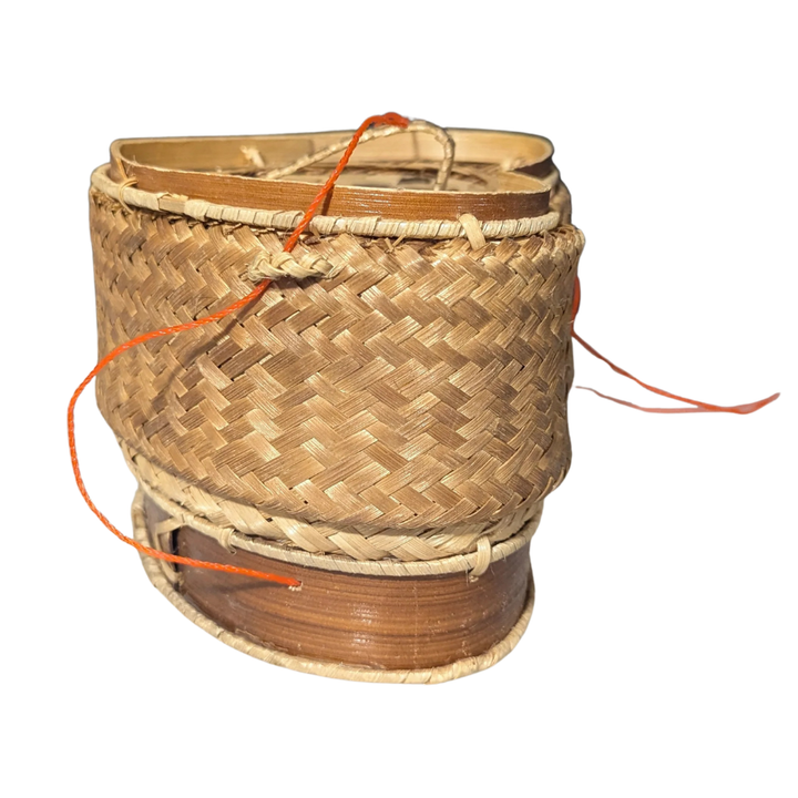 Woven rice basket with a spool of orange thread on a white background