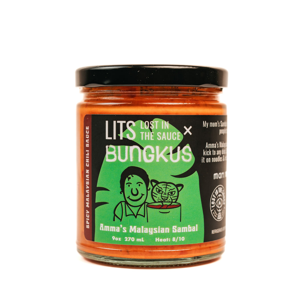 A jar of Amma's Malaysian Sambal hot sauce with a label that includes an illustration of a woman smiling and cooking. The text on the label also provides product information.