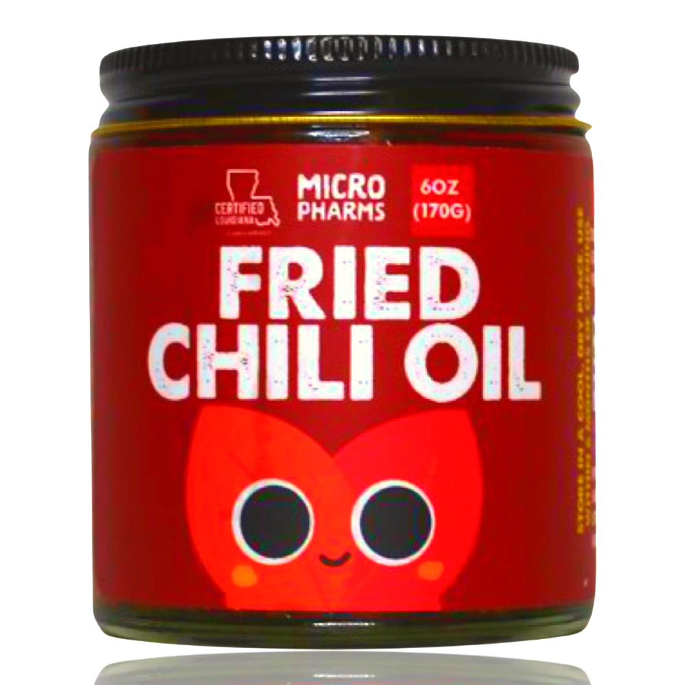 A jar of Micropharms Certified Organic Fried Chili Oil with a red label, black lid, and a cartoon chili pepper graphic, shown on a white background.