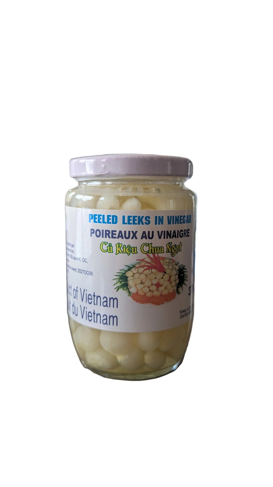 Jar of peeled leeks in vinegar on a wooden surface with a blurred background