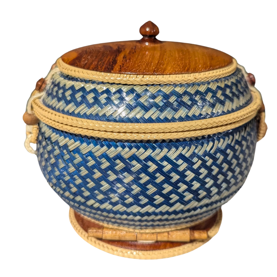 Woven basket with blue and beige pattern and wooden lid on a white background