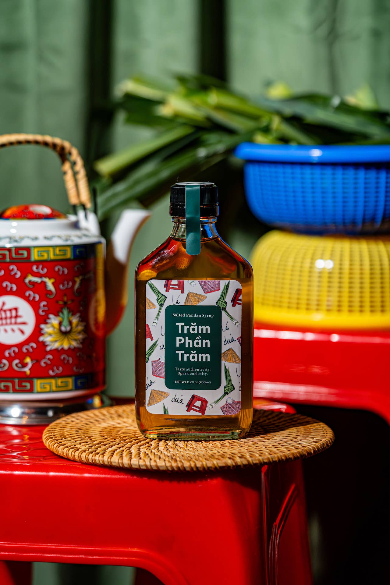 Bottle of Tram Phan Tram on a woven coaster with colorful background