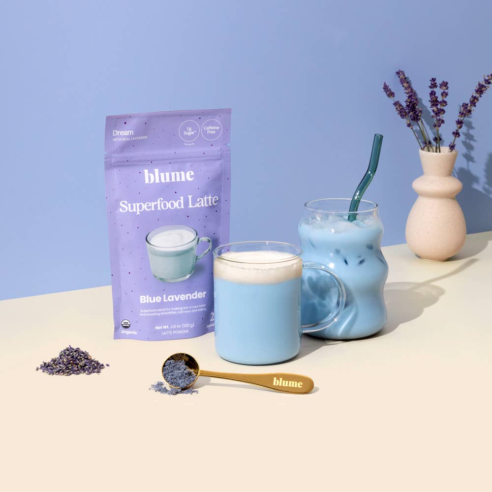 Blume Superfood Latte package with a glass of blue lavender latte on a light surface.