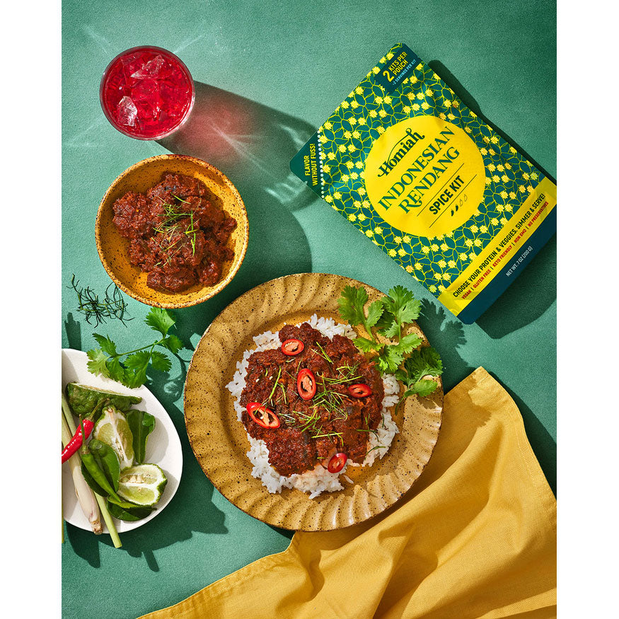 Indonesian Rendang dish with ingredients and a spice kit on a green background