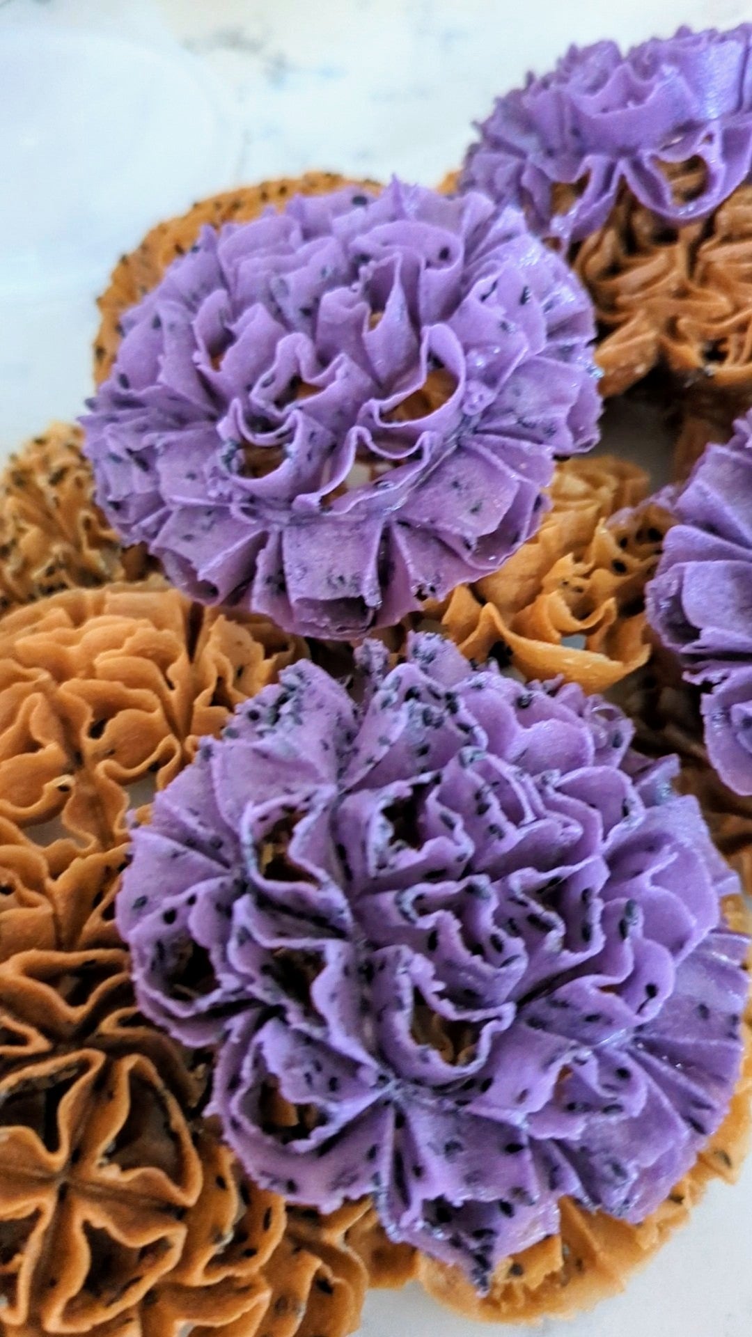 Brown and purple lotus blossom cookies with black sesame on a white background