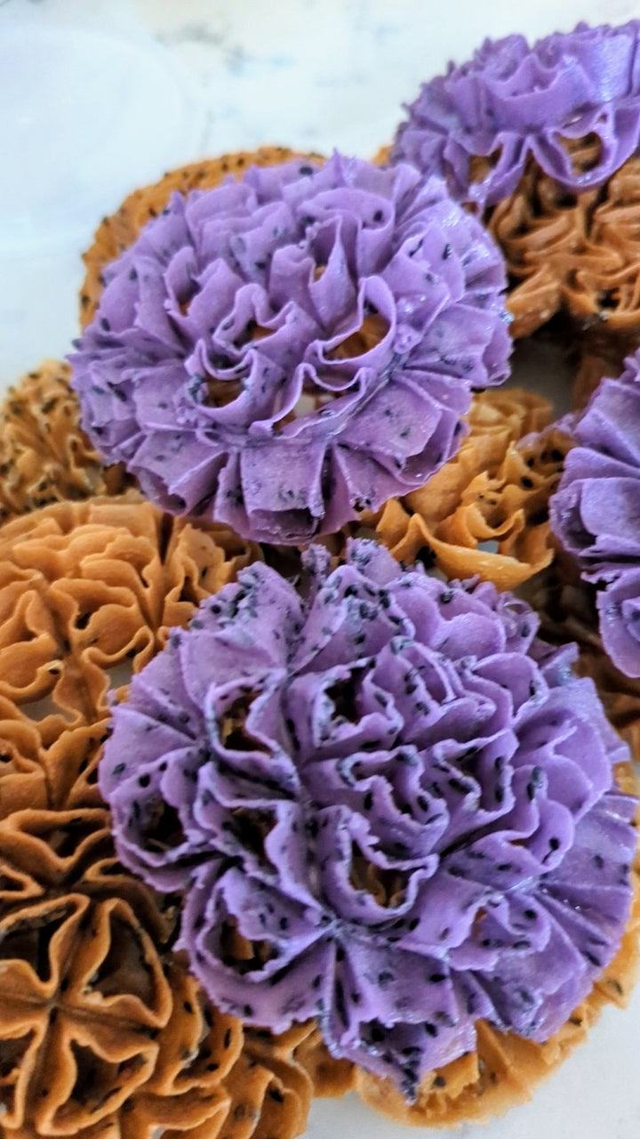 Brown and purple lotus blossom cookies with black sesame on a white background