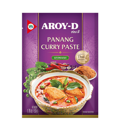 Packaging of Aroy-D Panang Curry Paste showing the product name, brand logo, and an image of a curry dish. The packet is purple with a Thai flag symbol, indicating the product is made in Thailand.